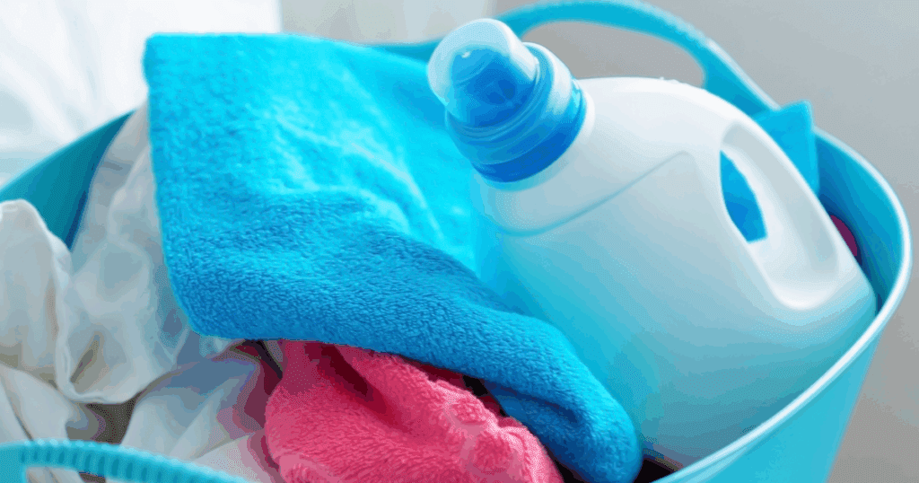 Freshly washed clothes folded neatly with fabric softener bottle beside them